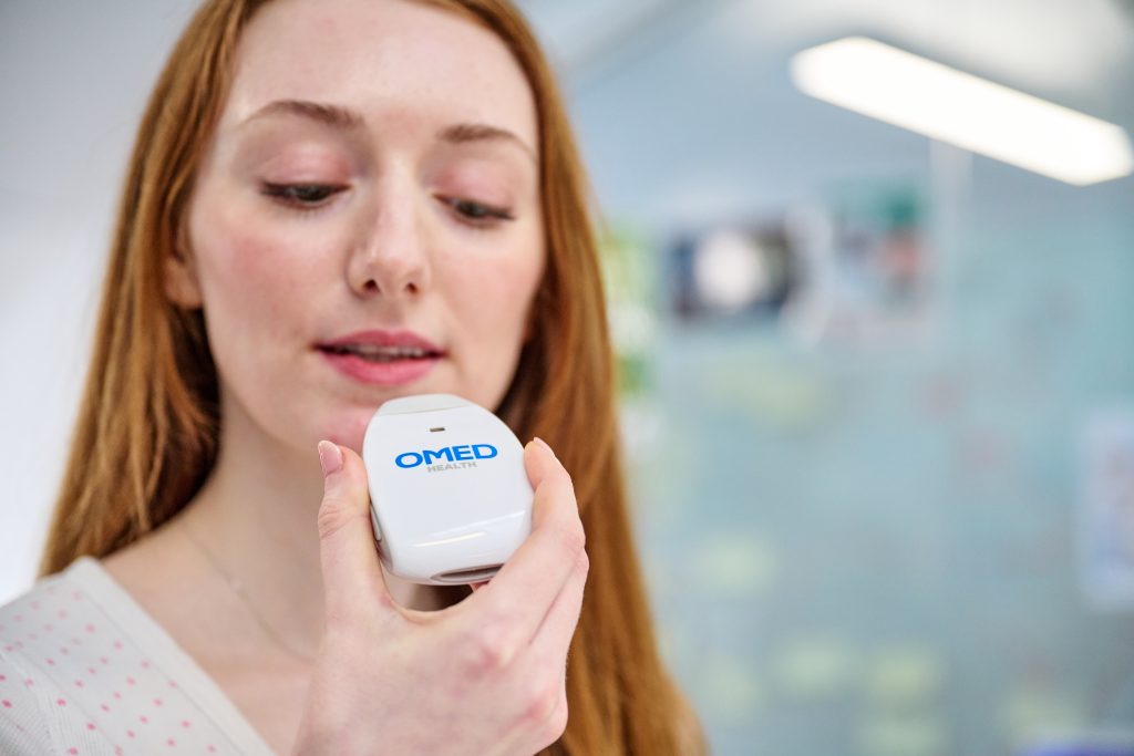 Woman breathing into Owlstone's breath biopsy device