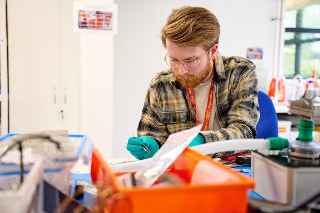 Man holding tweezers working on electronics